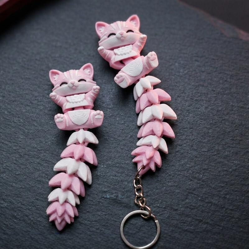 3D Printing Design Software - 3D プリントされたピンクの猫のキーホルダー、関節式の柔軟な尾が付いており、かわいい漫画のデザインで、バックパックの装飾に最適、猫愛好家へのギフトに最適です。